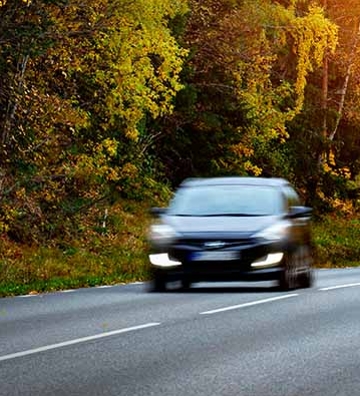 coche en carretera entre árboles con hojas naranjas