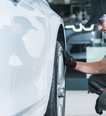 hombre a lado de llanta de coche revisando