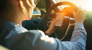 mujer manejando con celular en mano