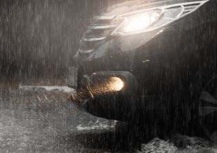 coche negro con luces prendidas bajo la lluvia