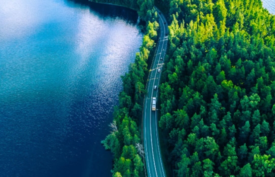 Carretera vista desde arriba junto a un lago azul y un bosque verde
